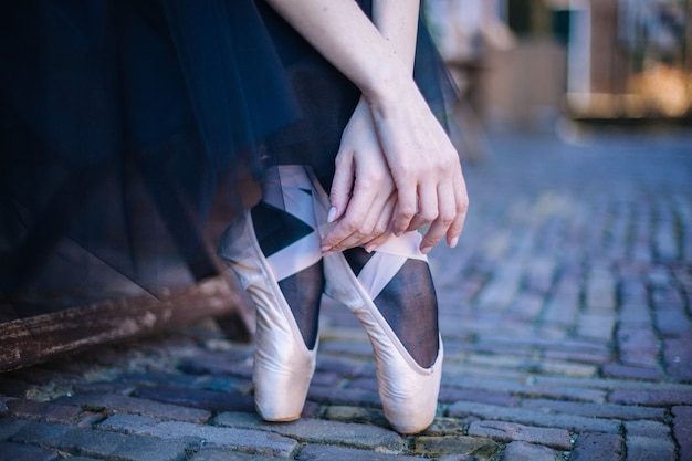 Mujer joven bailarina con el pelo rojo en traje de ballet bailando y zapatillas de punta está en pose hermosa bailando en la calle.