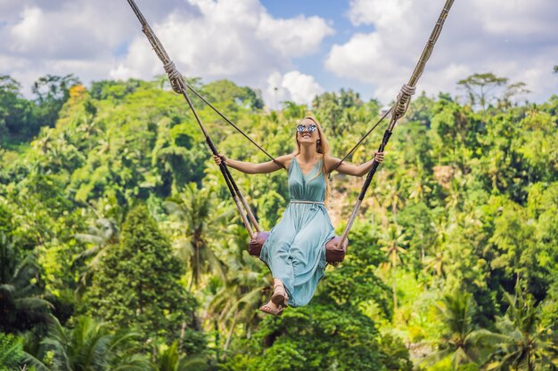 Mujer joven balanceándose en la selva tropical de la isla de Bali Indonesia Swing en los trópicos Swings trend of Bali