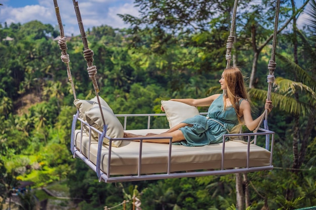 Mujer joven balanceándose en la selva tropical de la isla de Bali Indonesia Swing en los trópicos Swings trend of Bali