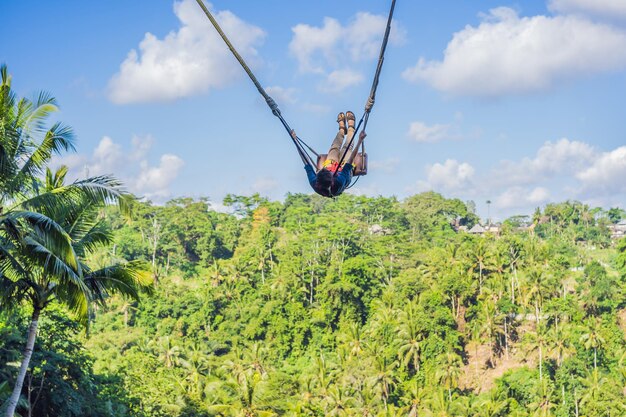 Mujer joven balanceándose en la selva tropical de la isla de Bali Indonesia Swing en los trópicos Swings trend of Bali