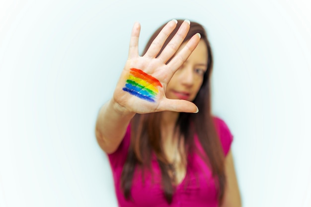 Mujer joven con la bandera LGBTI pintada en su mano sonriendo.