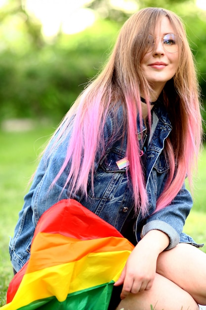 Mujer joven con bandera LGBTQ en la naturaleza