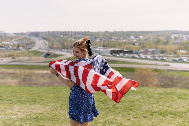 Una mujer joven con la bandera nacional de los Estados Unidos sobre sus hombros