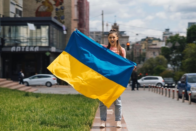 Mujer joven con bandera nacional de Ucrania en la calle