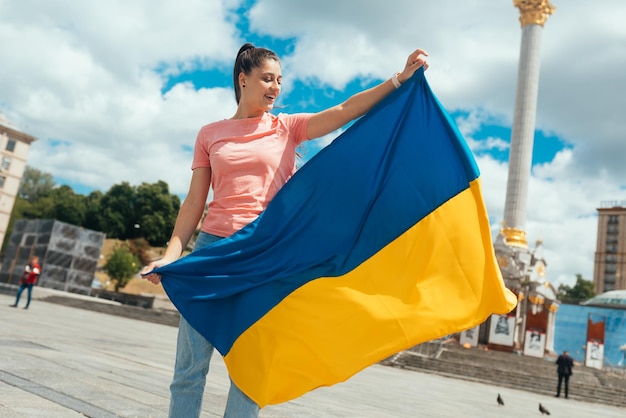 Mujer joven con bandera nacional de Ucrania en la calle