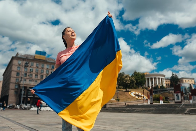 Mujer joven con bandera nacional de Ucrania en la calle