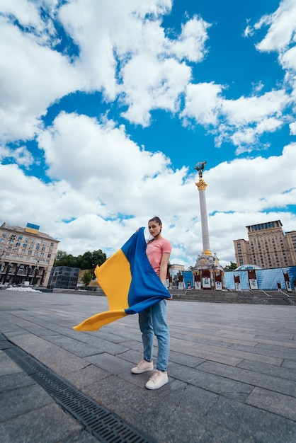 Mujer joven con bandera nacional de Ucrania en la calle