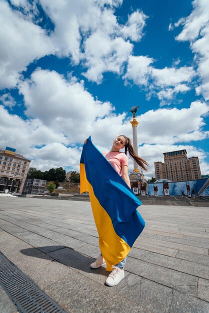 Mujer joven con bandera nacional de Ucrania en la calle