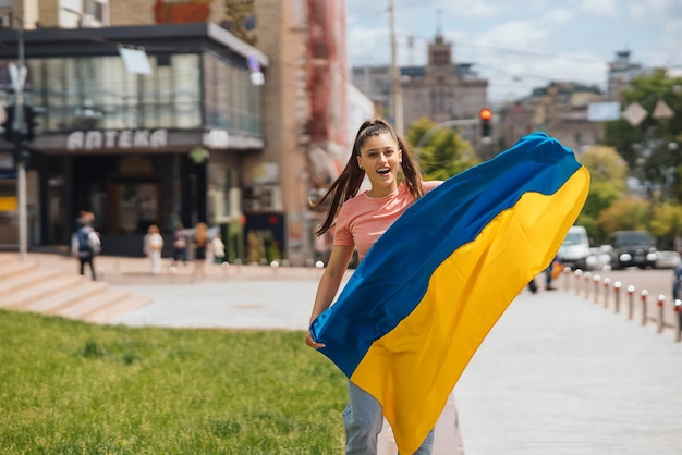 Mujer joven con bandera nacional de Ucrania en la calle