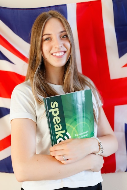 Mujer joven con banderas de países de habla inglesa. Estudiante de inglés con la bandera británica al fondo. Inglés, aprender, estudiar.