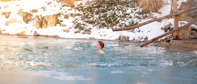 Mujer joven de baño en un lago congelado después de la sauna.