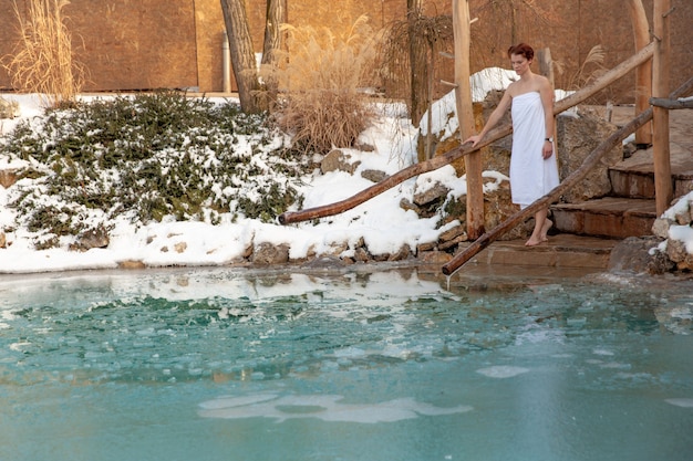 Foto mujer joven de baño en un lago congelado después de la sauna.