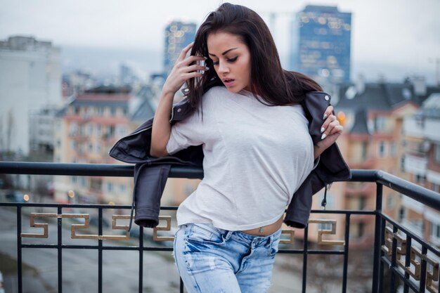 Foto mujer joven en la barandilla en la ciudad