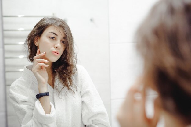 Mujer joven en bata de baño de pie en el baño