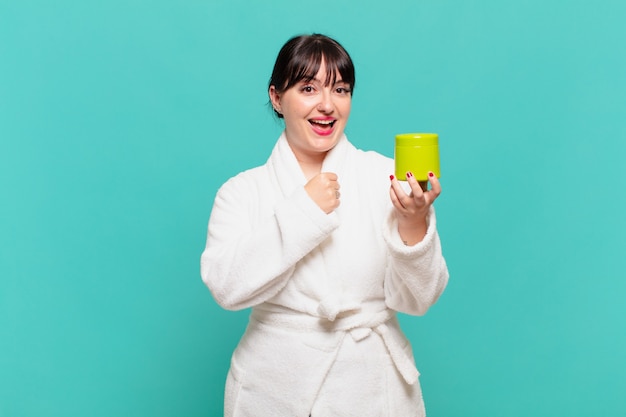 Mujer joven en bata de baño que se siente feliz, positiva y exitosa, motivada cuando se enfrenta a un desafío o celebra buenos resultados