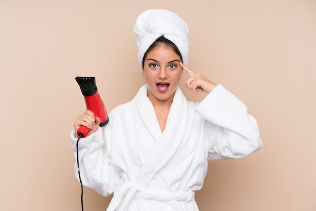 Mujer joven en bata de baño con secador de pelo con la intención de darse cuenta de la solución