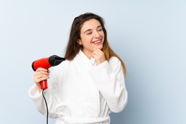 Mujer joven en una bata de baño con secador de pelo pensando una idea y mirando de lado