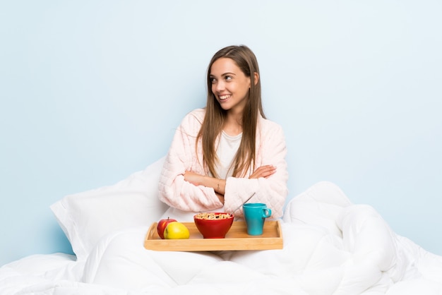 Mujer joven en bata con desayuno mirando hacia el lado