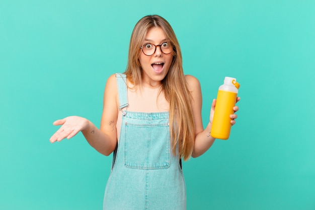 Mujer joven con un batido asombrado, conmocionado y asombrado con una sorpresa increíble