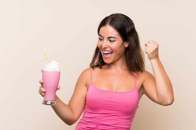 Mujer joven con batido de fresa celebrando una victoria