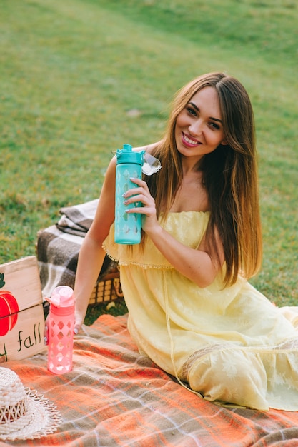 mujer joven bebe agua en un picnic