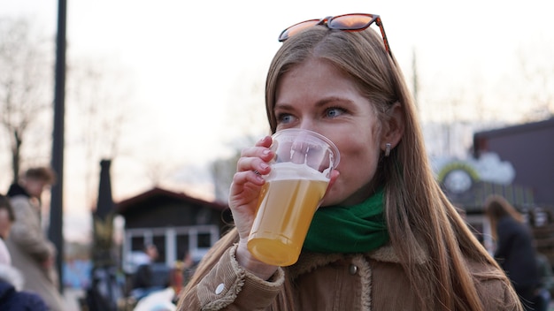 Mujer joven bebe cerveza ligera comida callejera y patio de comidas