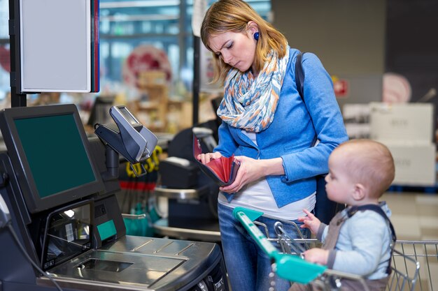 Mujer joven con bebé pagando con auto checkout