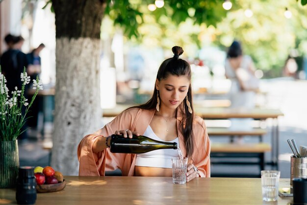 Mujer joven con una bebida fría sentada en un café en la calle