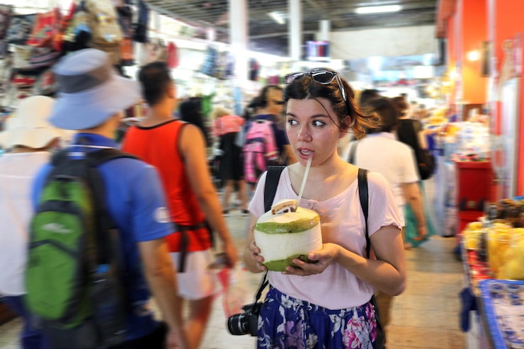 Foto mujer joven bebiendo agua de coco en el mercado por la noche