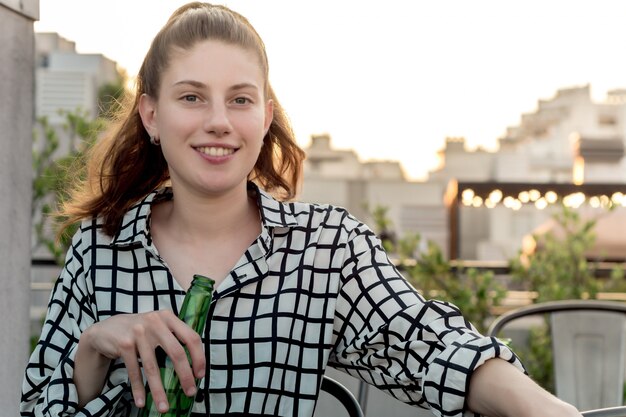 Mujer joven bebiendo en la azotea al aire libre