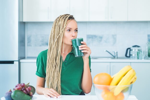 Mujer joven bebiendo batido verde