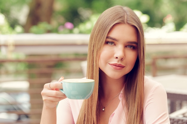 Mujer joven bebiendo café en un café al aire libre