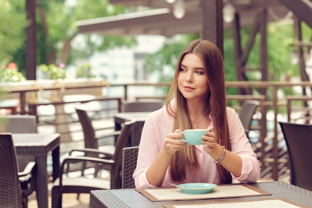 Mujer joven bebiendo café en un café al aire libre