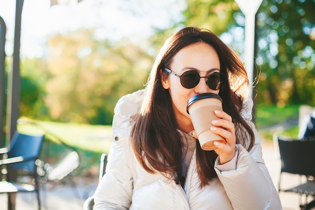 Mujer joven bebiendo café en la cafetería al aire libre