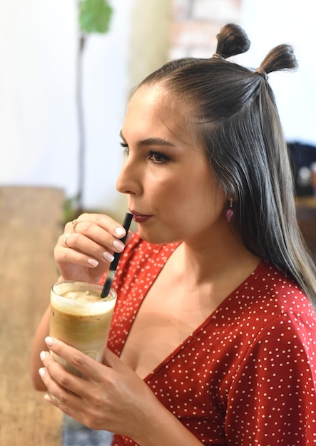 Mujer joven bebiendo café helado en una cafetería.