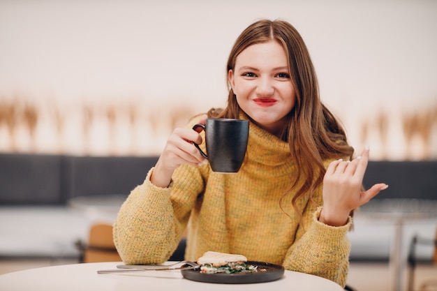 Mujer joven bebiendo café por la mañana en el café