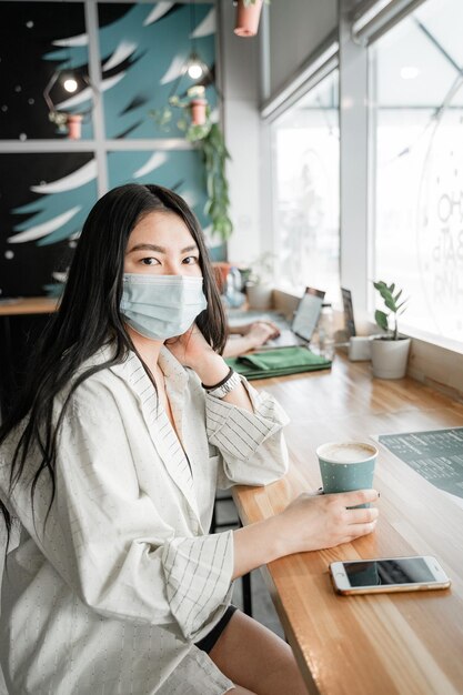 Mujer joven bebiendo café en la mesa