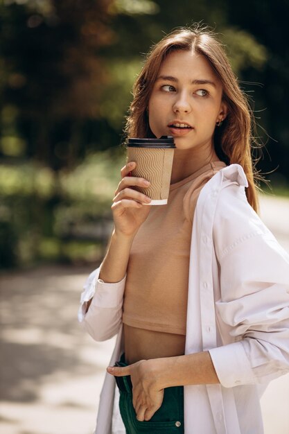 Mujer joven bebiendo café en el parque