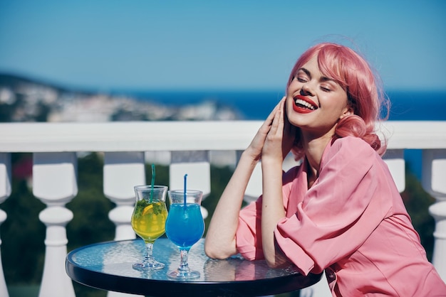 Mujer joven bebiendo un cóctel en la terraza mujer feliz relajante