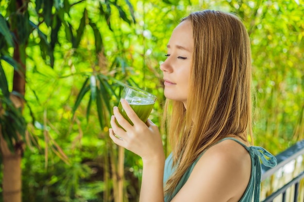 Foto mujer joven bebiendo jugo de apio saludable bebiendo un ramo de apio sobre un fondo de madera