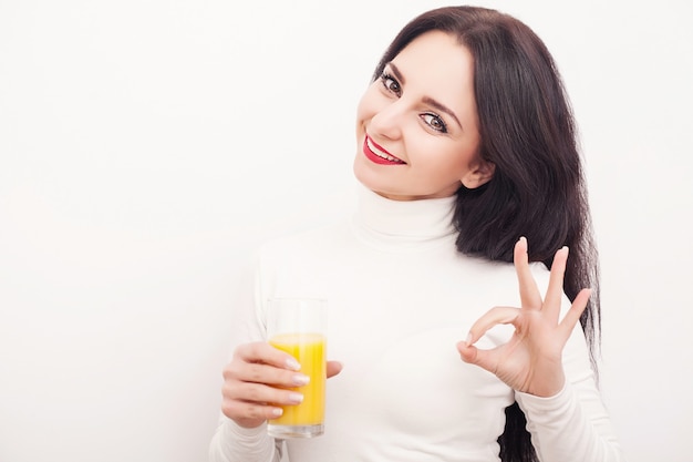 Mujer joven bebiendo jugo de naranja fresco