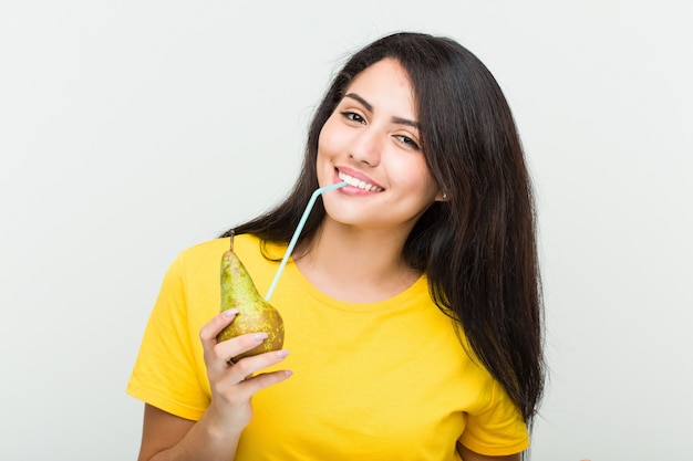 Mujer joven bebiendo un jugo de pera con una pajita