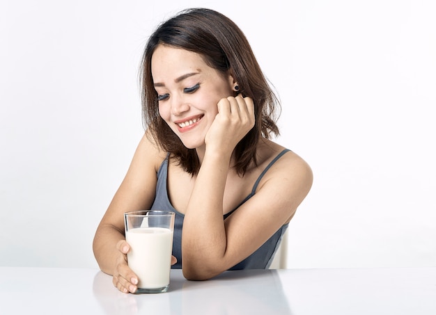 Mujer joven bebiendo leche en la mesa