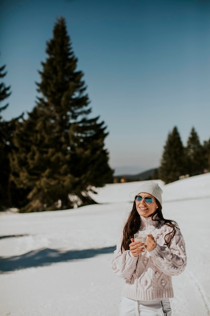 Mujer joven bebiendo limonada en la pista de esquí de montaña