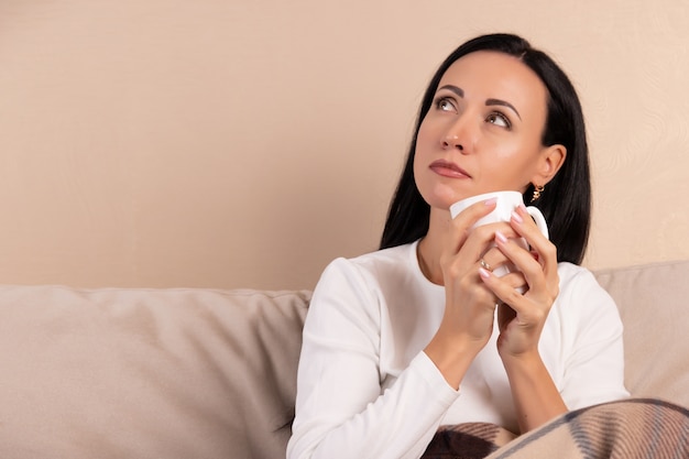 Mujer joven bebiendo una taza de té en el sofá