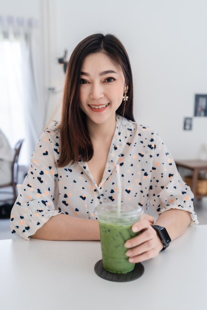 Mujer joven bebiendo té verde con leche en un café