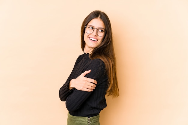 Mujer joven en beige riendo y divirtiéndose.