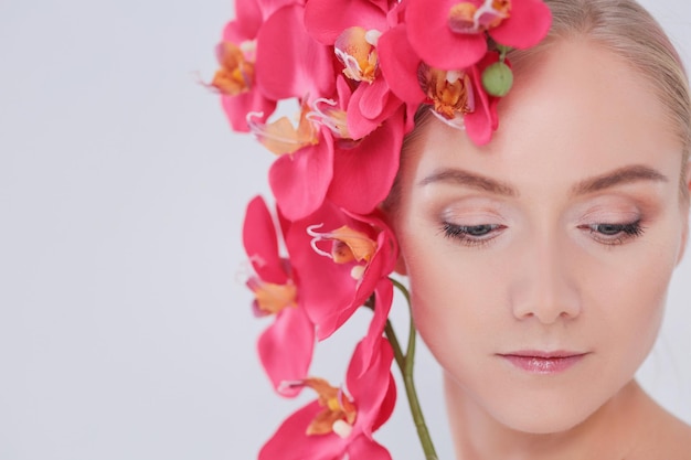 Mujer joven belleza con flor cerca de la cara.