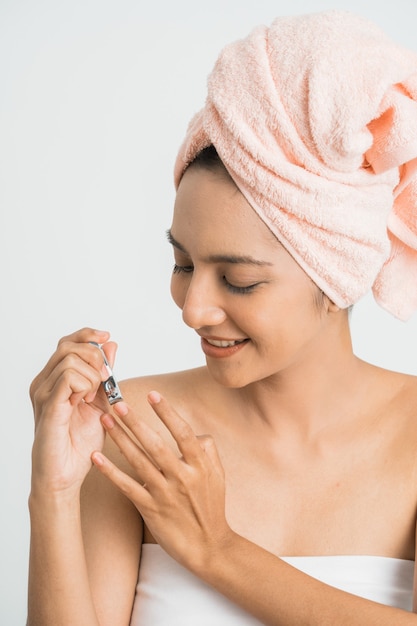 Foto mujer joven de la belleza que hace la manicura con el corte de la uña sobre la pared blanca concepto de atención saludable.