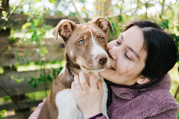 Mujer joven besando y jugando con su cachorro y disfrutando el momento